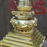 Angled close up of the mid section of the back showing raised ornament work and coloured inlay dots on the band beneath the spire.