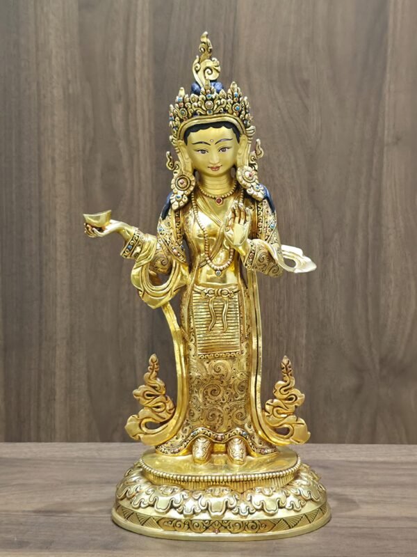 Full front view of Yeshe Tsogyal gold statue holding a kapala offering bowl and standing on a lotus base.