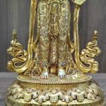 Detail of the masterfully hand-chased floral skirt and feet resting on the double lotus base of the gold Mandarava statue.