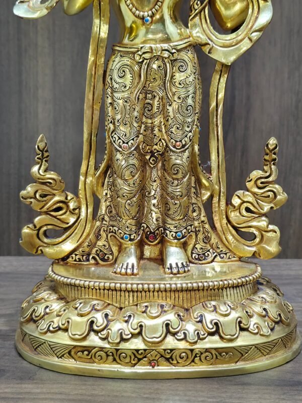 Detail of the masterfully hand-chased floral skirt and feet resting on the double lotus base of the gold Mandarava statue.