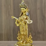 Right side profile of gold plated Yeshe Tsogyal statue holding a kapala offering bowl.