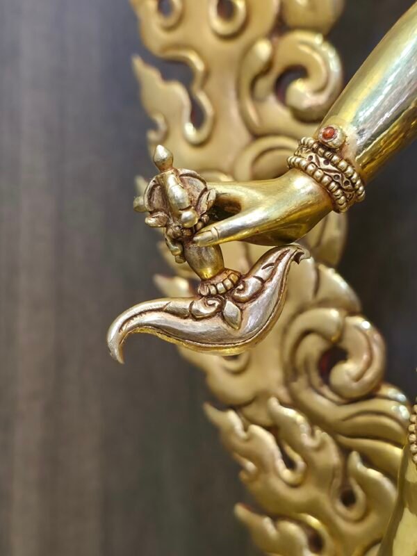Macro close-up of the Vajrayogini statue's right hand holding the kartika, a curved flaying knife symbolizing the severing of ego and ignorance.