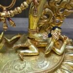 Detailed close-up of the Vajrayogini statue base showing the trampling of prostrate figures on a lotus pedestal.