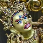 Close-up of the Vajrayogini face meticulously painted with pure gold powder featuring an upward gaze.