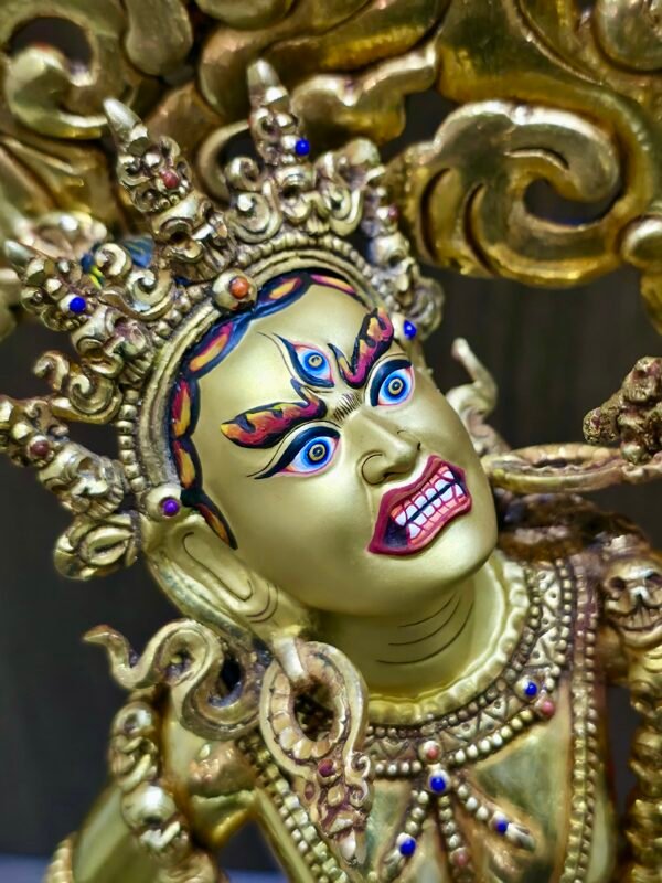 Close-up of the Vajrayogini face meticulously painted with pure gold powder featuring an upward gaze.