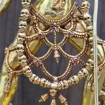 Macro detail of 24K gold plated Vajrayogini statue showing intricate bone apron, skull garland, and gemstone inlays on the waist.