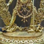 Close up of Vajrayogini trampling Kalaratri and Bhairava on an engraved gold lotus base, symbolizing the defeat of ignorance and ego.