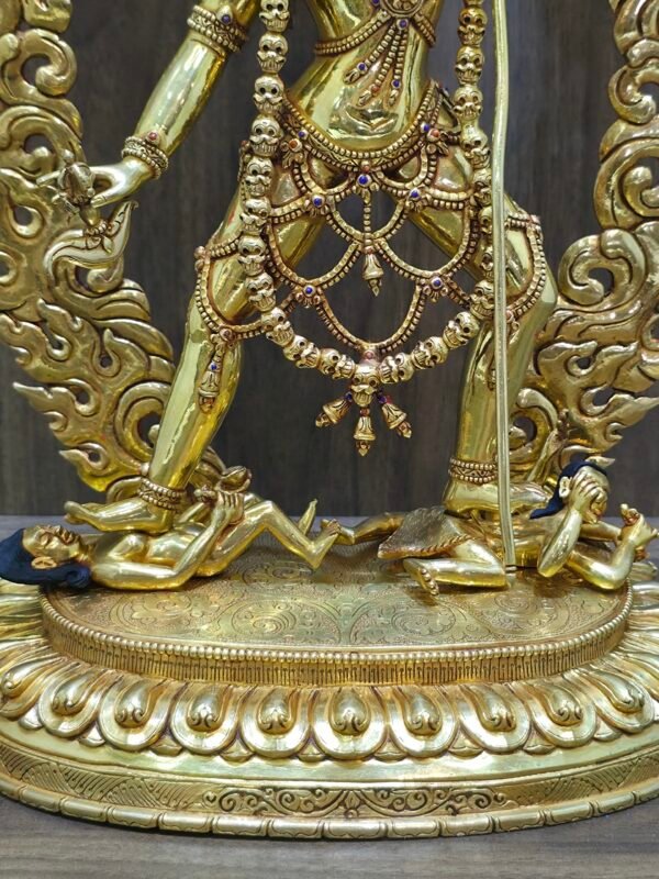 Close up of Vajrayogini trampling Kalaratri and Bhairava on an engraved gold lotus base, symbolizing the defeat of ignorance and ego.