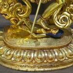 Close up of Dorje Phagmo Vajravarahi base showing the goddess stepping on a prostrate figure on an engraved lotus style pedestal.