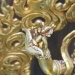 Macro detail of Vajravarahi right hand holding the kartika flaying knife against a gold fire aura.