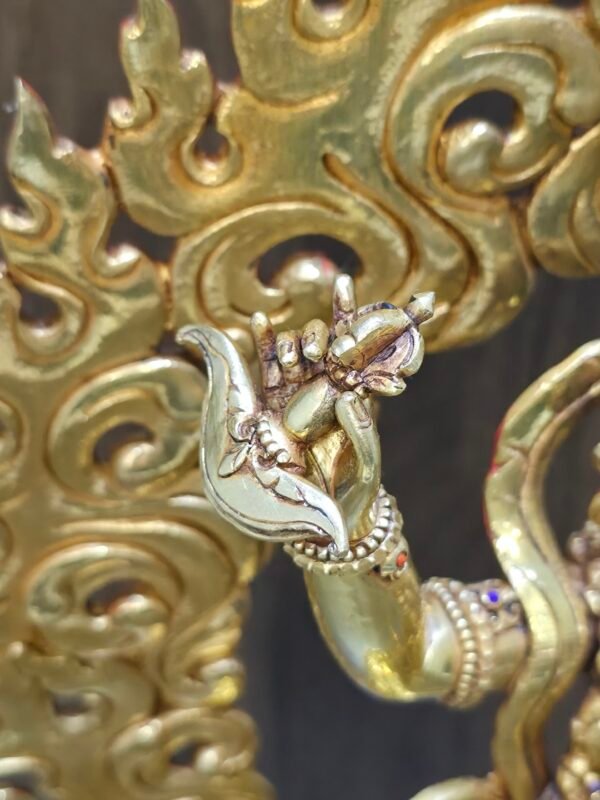Macro detail of Vajravarahi right hand holding the kartika flaying knife against a gold fire aura.