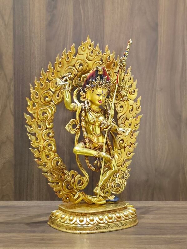 Left view of Dorje Phagmo Vajravarahi statue with gold plated finish, ornate halo and upright staff shown in profile.