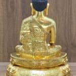 Full rear view of the gold-plated Buddha statue highlighting the continuous hand-chased floral engravings across the monastic robes.