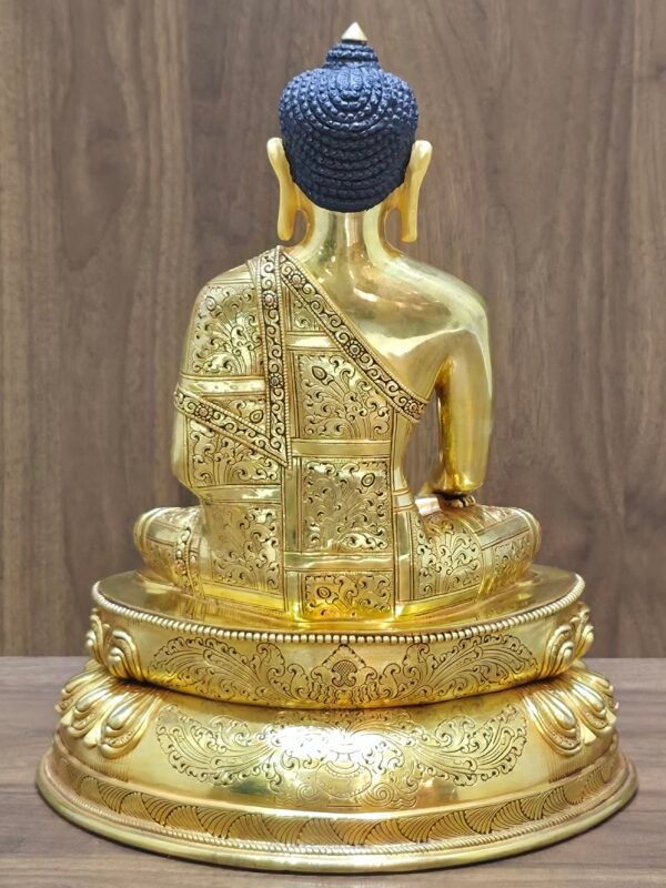 Full rear view of the gold-plated Buddha statue highlighting the continuous hand-chased floral engravings across the monastic robes.