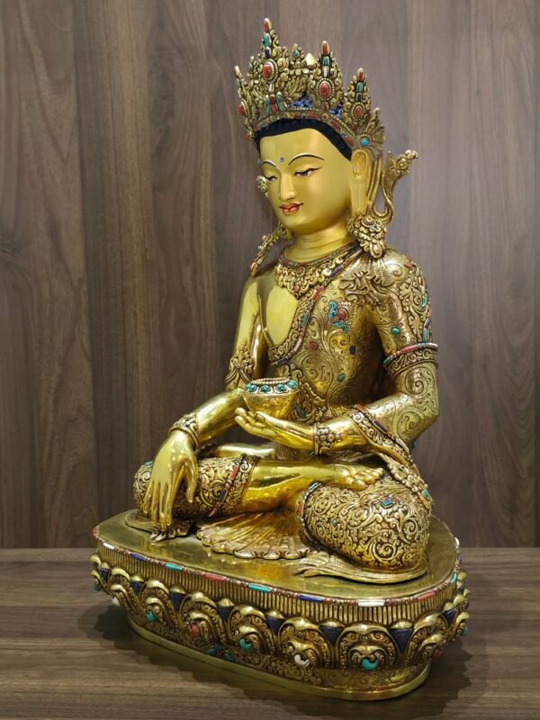 Three quarter front view of Crown Shakyamuni Buddha statue with gold plated copper finish, ornate robe, crown and lotus base.