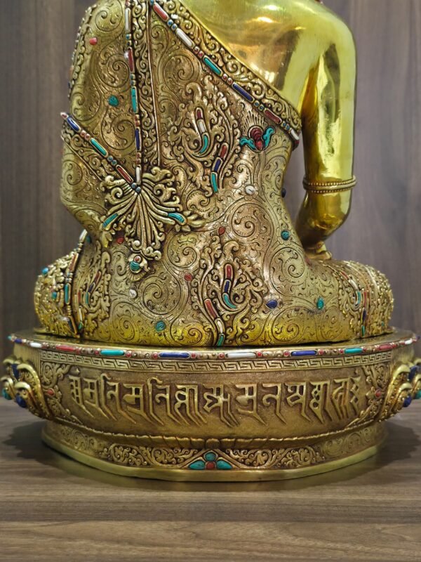 Rear lower view of Crown Shakyamuni Buddha statue showing engraved robe, decorated base and inscription detail.