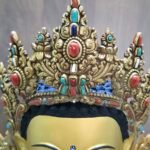 Close up of the ornate crown on Crown Shakyamuni Buddha statue with red coral, turquoise, lapis and conch shell details.