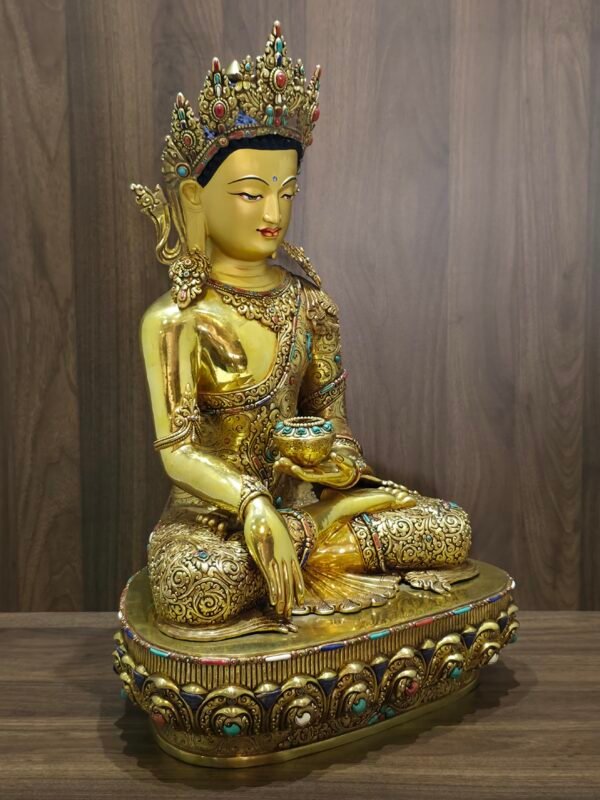 Angled front view of Crown Shakyamuni Buddha statue holding an alms bowl, with gold plated robes and decorative inlay.