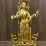 Full front view of Mandarava statue on lotus base holding a ritual vase.