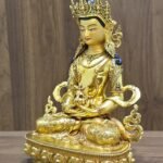 Left-facing angled view of Amitayus Buddha showing the long-life vase, layered jewellery, patterned garments and curling scarf ornaments.