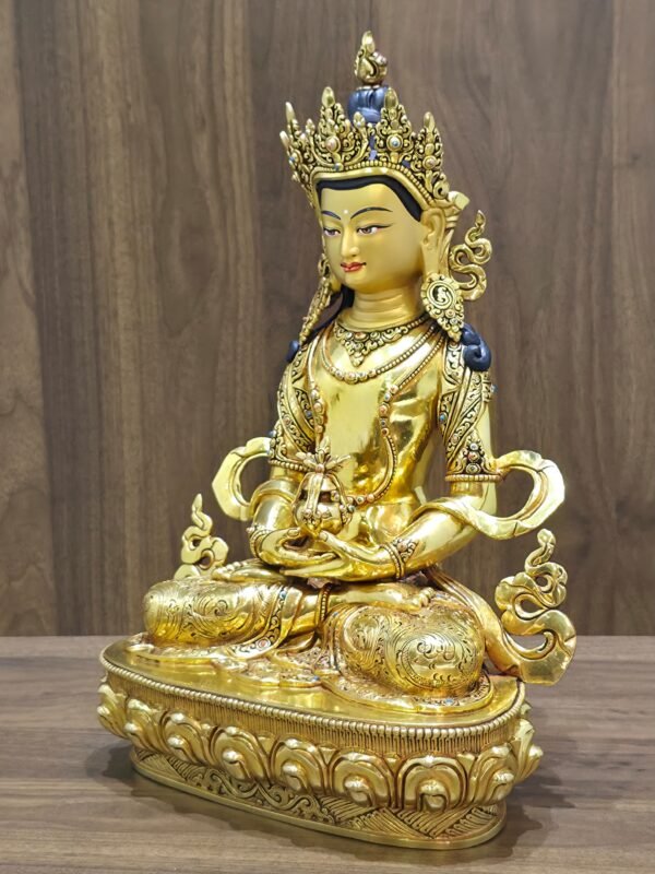 Left-facing angled view of Amitayus Buddha showing the long-life vase, layered jewellery, patterned garments and curling scarf ornaments.