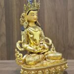Right-facing angled view of Amitayus Buddha showing the gold plated copper body, ornate crown and sculpted lotus pedestal.
