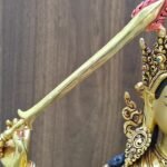 Close-up of the Manjushri statue’s raised sword, showing its gold-plated blade and red flame detailing at the tip.