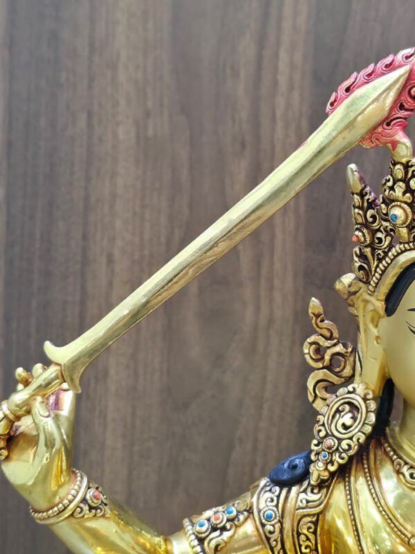 Close-up of the Manjushri statue’s raised sword, showing its gold-plated blade and red flame detailing at the tip.