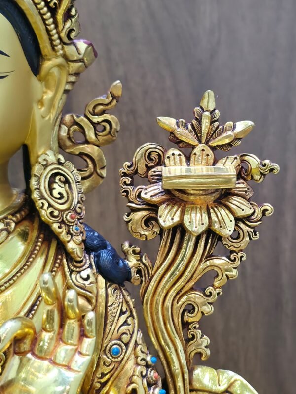 Close-up of the scripture resting on a lotus beside Manjushri’s left shoulder, with detailed petals and curling foliage.