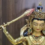 Close-up of Manjushri’s raised sword, showing engraved details along the gold-plated blade and red flames around its tip.
