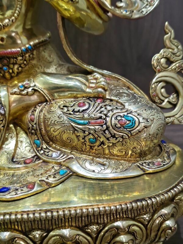 Close-up of Manjushri’s engraved garments, showing raised scrolling motifs with red coral, imitation turquoise and white conch shell inlays.