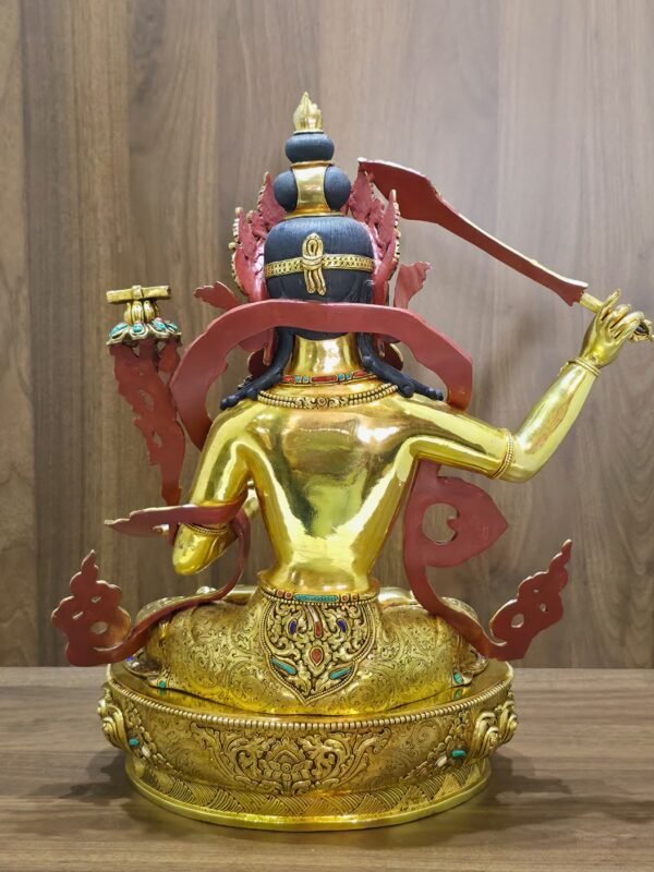Rear view of Manjushri, showing dark blue hair, red-painted ornament backs, a gold-plated back and engraved garments and pedestal.