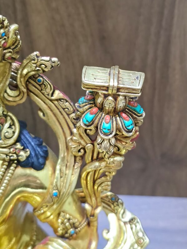 View from above of Manjushri’s lotus-supported scripture, showing its engraved cover, central band and coloured lotus-petal accents.