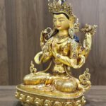 Left-facing view of four-armed Chenrezig statue showing the lotus, joined hands and ornate lotus pedestal.