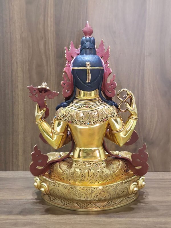 Rear view of Chenrezig statue showing dark blue hair, decorated shoulders and engraved garments and lotus pedestal.