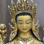 Close-up of the Green Tara statue’s painted face, ornate crown and red and blue decorative accents.