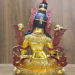 Rear view of the White Tara statue in 24K gold plated copper, showing dark painted hair, patterned garments and the decorated lotus base.