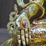 White Tara Buddhist statue in 24K gold plated copper, close-up of the painted eye on the lowered right palm.