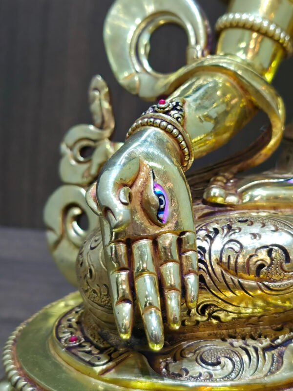 White Tara Buddhist statue in 24K gold plated copper, close-up of the painted eye on the lowered right palm.