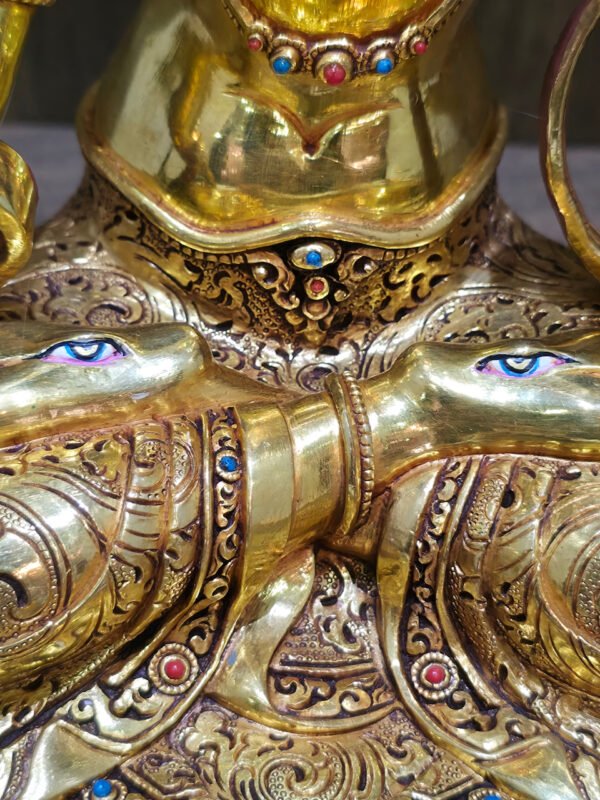 White Tara statue in 24K gold plated copper, close-up of the painted eyes on both soles and intricately patterned garments.